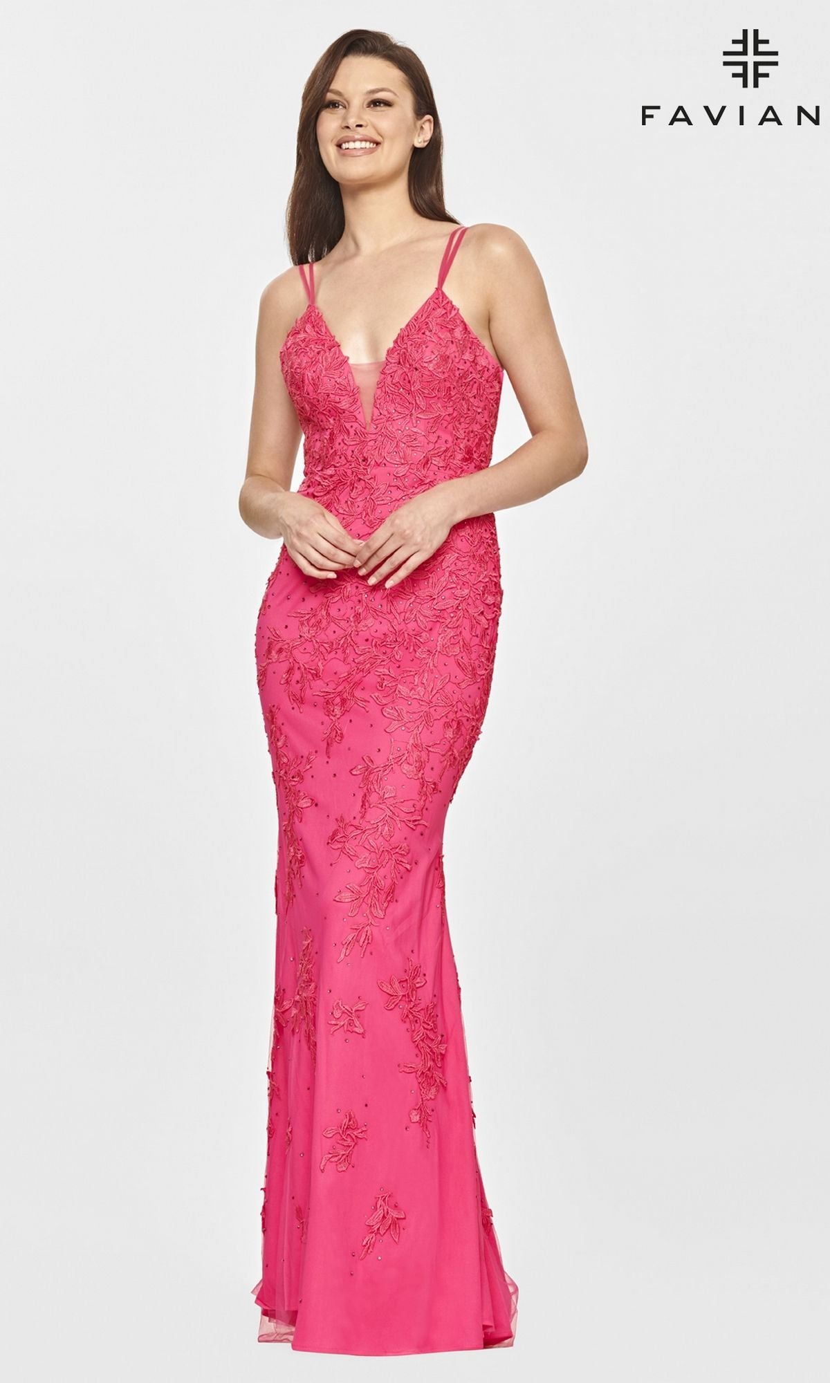 A woman smiles against a plain background wearing the Faviana S10813 Long Lace Hot Pink Prom Dress with floral embroidery. The Faviana logo is displayed in the top right corner.